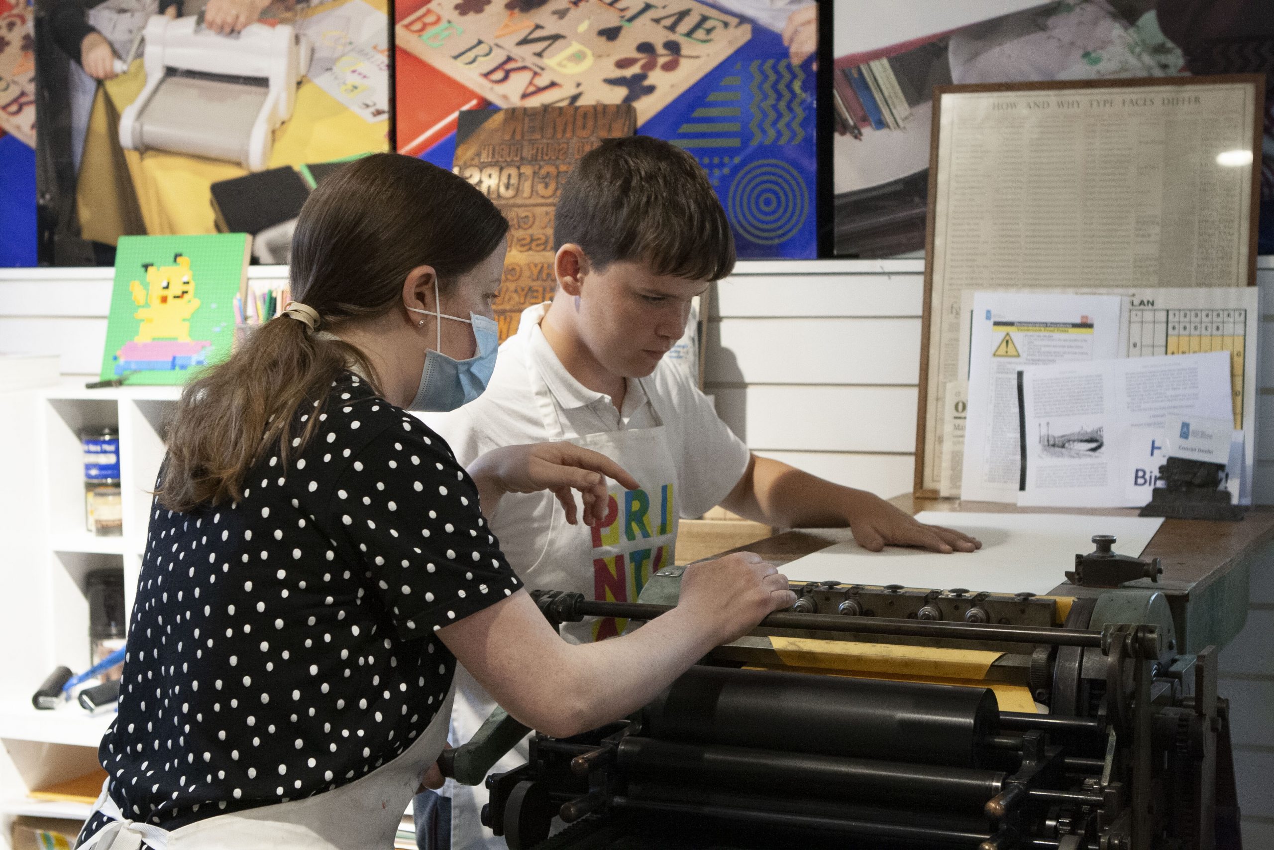 Mary Plunkett showing students how to use the letterpress for printing.