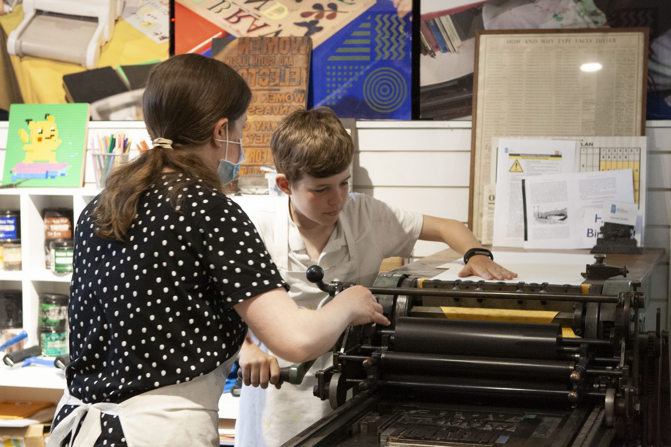 Mary Plunkett showing students how to use the letterpress for printing.