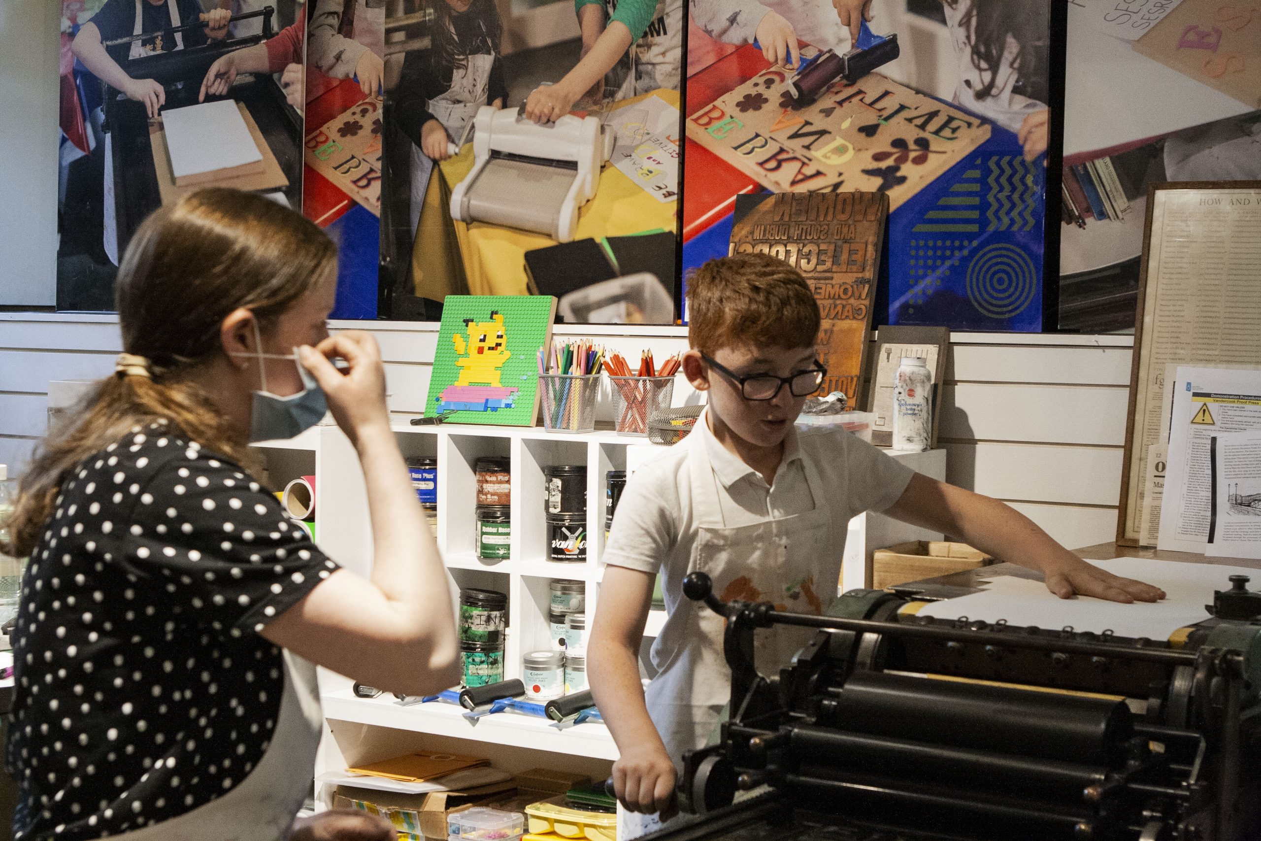 Mary Plunkett showing students how to use the letterpress for printing.